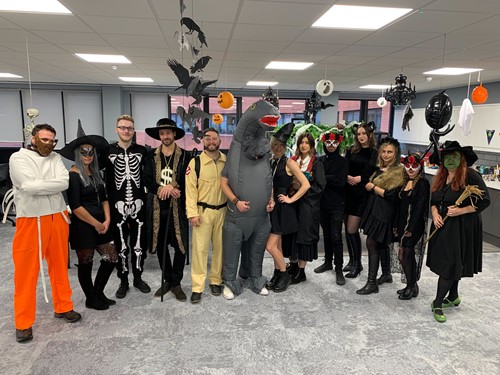 An office with a line of staff dressed spookily for Halloween